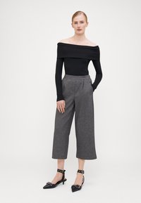 Svart avskjærmet ribbet topp, grå brede bukser med en subtil tekstur, og svarte spisse slingback hæler med spenneaccenter.