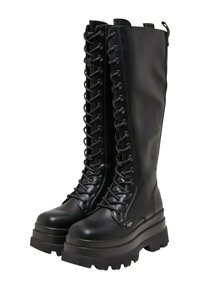 Borceguíes negros con cordones y caña alta, hechos de cuero suave. Suela de plataforma gruesa con un patrón de banda de rodadura robusto, detalles de costura en contraste.