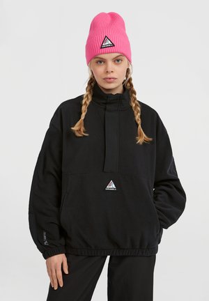 Schwarzer Fleece-Pullover mit hohem Kragen und elastischem Bund, mit einem dreieckigen Logo. Rosa gerippte Mütze mit Logo-Patch.