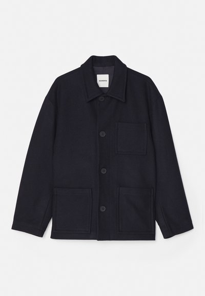 Námornícky modrá bunda z vlnenej zmesi s golierovým výstrihom, predným zapínaním na gombíky a dvoma prednými vreckami. Hladká textura a jednoduchý dizajn.