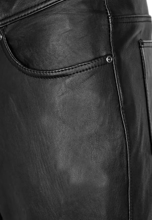 Schwarze Lederhose mit glatter Textur, seitlichen Taschen und kontrastierenden Nähten. Der Stoff wirkt strapazierfähig und strukturiert.