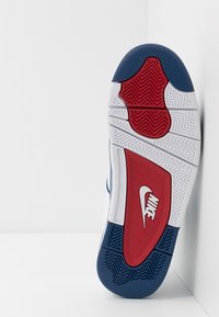 Nike sneaker zool in wit, blauw en rood. Heeft een textuur rubber voor grip, een prominent logo en een opvallend loopvlakpatroon.