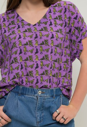 Haut violet à col en V avec un imprimé répétitif de tigres jaunes et noirs ; manches courtes ; associé à un short en denim bleu taille haute.