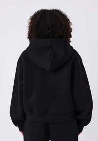 Sudadera negra con capucha de ajuste holgado, con puños y cintura elásticos. Material suave con textura lisa.