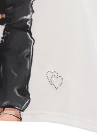 Witte stof met een gedrukte design van een figuur in zwarte kleding. Accentueert met zilveren rhinestones die een hartvorm creëren.