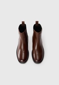 Brown leather ankle boots with a glossy finish, featuring a rounded toe and pull tab at the back, set on a contrasting black sole.