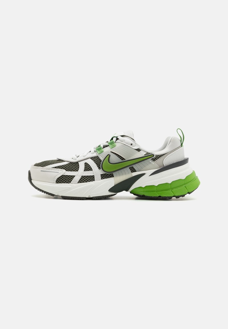 Baskets Nike blanches et grises avec accents verts, panneaux en mesh, semelle amortie et logo Swoosh vert sur le côté.