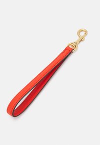 Czerwony skórzany pasek na nadgarstek z złotym metalowym zapięciem, zaprojektowany do przyczepiania kluczy lub małych akcesoriów.