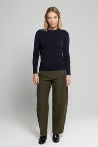 Marineblauwe trui met lange mouwen en een ronde hals, gecombineerd met olijfgroene wijde broek en zwarte enkelboots. Minimalistisch ontwerp, geen patronen.