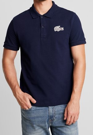 Marineblaues Poloshirt aus Baumwolle mit kurzen Ärmeln, zwei Knöpfen und einem strukturierten, gestickten Logo auf der linken Brustseite.