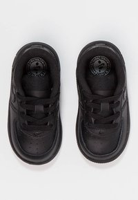 Svarta lädersneakers med perforerat tåparti, svarta snören och en cirkulär logotyp på tungan, samt en texturerad gummisula.