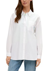 White button-up shirt with a chest pocket and long sleeves; made of smooth fabric with a relaxed fit; accented by a subtle blue detail in the pocket.