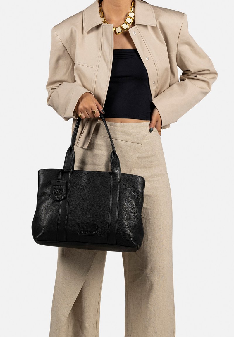 Borsa a tracolla nera in pelle con doppio manico, caratterizzata da una superficie texturizzata, un'etichetta decorativa e sottili dettagli di cucitura verticale.