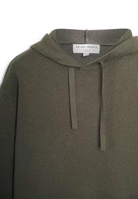 Sudadera verde oliva hecha de una suave mezcla de algodón. Presenta un corte holgado, textura acanalada y un cordón en la capucha.