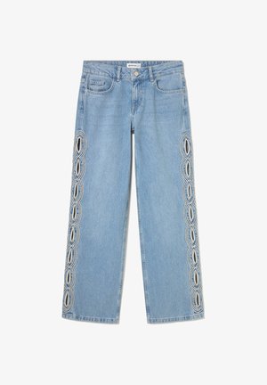 Pantalones vaqueros azul claro de corte recto con patrones ovalados recortados bordeados por costuras blancas que recorren ambos lados exteriores de las piernas.