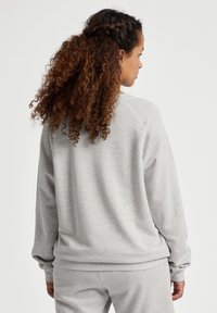 Szara bluza z ribbowymi mankietami i dołem, o luźnym kroju i miękkiej fakturze. Tył ma prosty wzór bez widocznych logo.