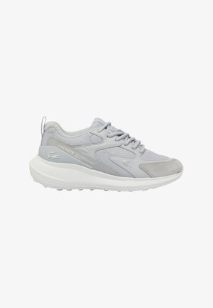 Hellgraue Sneakers, die eine Kombination aus strukturiertem Mesh und Wildledermaterialien aufweisen, mit einer weißen Gummisohle und Schnürdesign. Lacoste-Branding sichtbar.