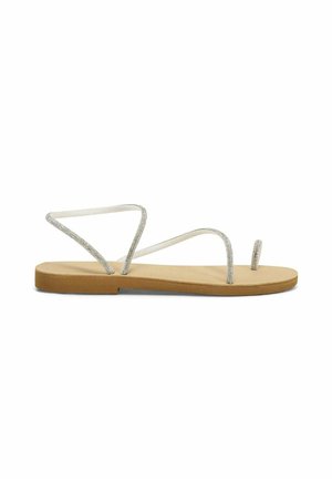 Platte sandalen met een beige zool en zilverkleurige glittersstraps. De straps vormen een open teen ontwerp, wat minimale bedekking en flexibiliteit biedt.