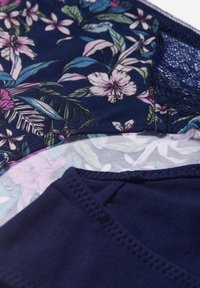Granatowa bluzka w kwiaty z żywym tropikalnym wzorem, w różowe i zielone liście. Wycięcie w koronkowym detalu oraz gładka, miękka tekstura materiału.