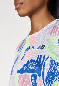 Lühikeste varrukatega, võrkmaterjalist t-särk, millel on värvikas graafiline trükk roosa, rohelise ja sinise värviga, ning rinnal "New Balance" logo.