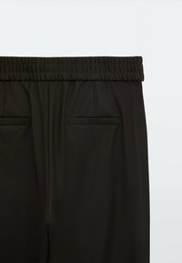 Svarta byxor med en bred elastisk midja, två bakfickor och en slät textur, utformade för komfort och lätthet vid påtagning.