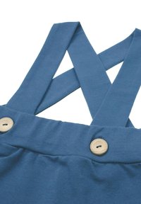 Niebieskie bawełniane ogrodniczki z paskami na krzyż na plecach, ozdobione drewnianymi guzikami, o miękkiej, gładkiej fakturze. Prosty design, bez wzorów i ozdób.