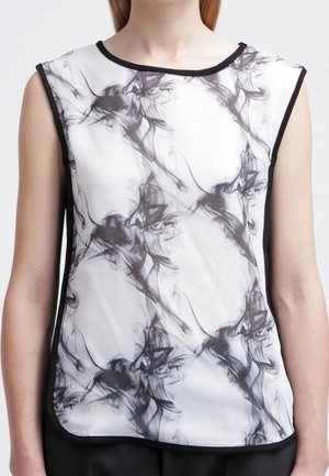 Biały top bez rękawów z czarnym abstrakcyjnym wzorem przypominającym dym oraz czarną lamówką na dekolcie i pod pachami.