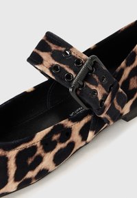 Chaussure plate Mary Jane en tissu doux avec imprimé léopard, dotée d'une boucle noire avec œillets et d'un profil bas, idéale pour un usage décontracté.