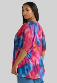 Maglietta fluente a maniche corte con un vivace motivo tie-dye nei colori rosa, blu e viola. Tessuto morbido con scollatura rotonda e bordi delle maniche scallop.