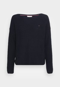 Pull en tricot bleu marine avec col large, épaules tombantes et accents en tricot torsadé sur les côtés. Comprend un petit logo sur la poitrine.