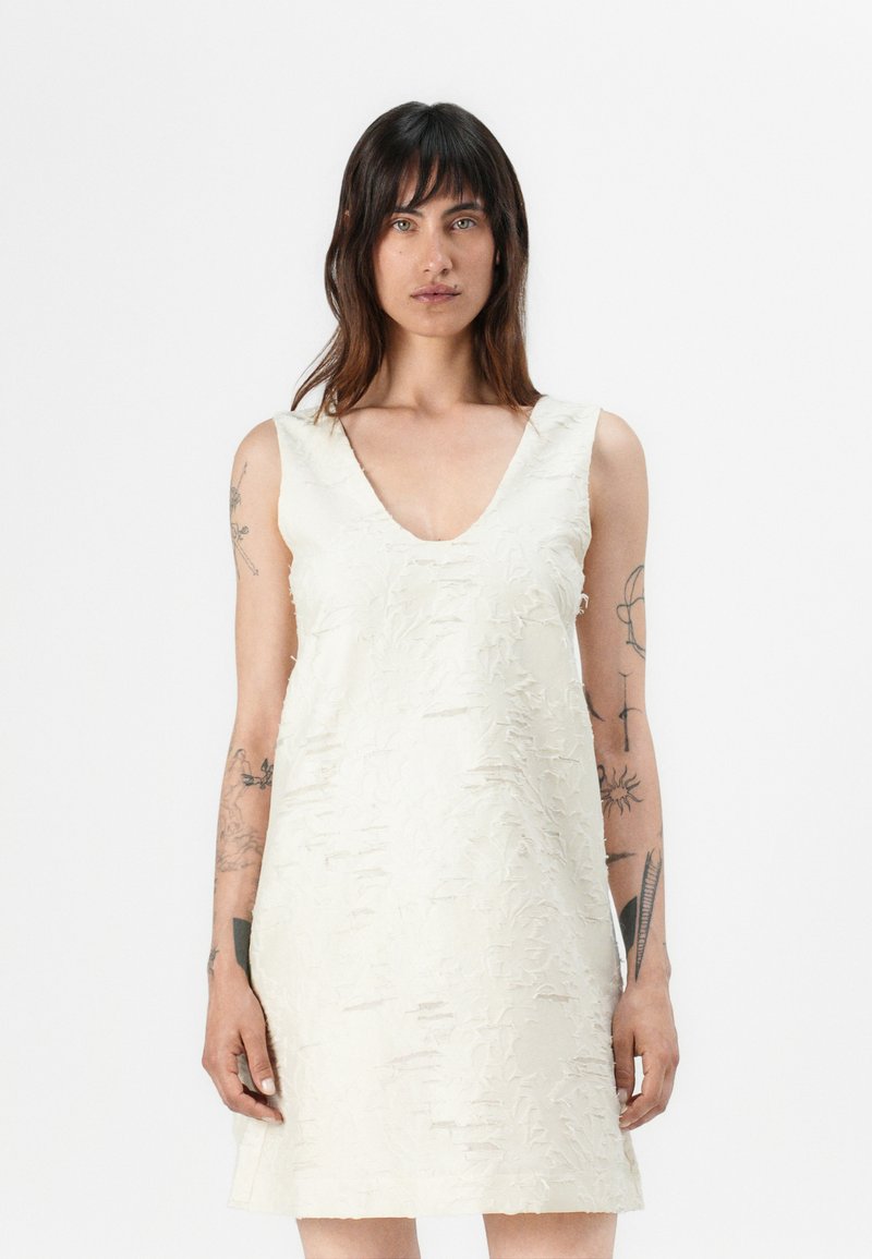 Hihaton mekko off-white-värissä, jossa on V-pääntie ja teksturoitu pinta hienovaraisilla kuvioilla. Polveen ulottuva, rento malli.