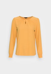 Top giallo a maniche lunghe con scollatura a chiave. Presenta dettagli arricciati sulla spalla e polsini elasticizzati per una vestibilità comoda. Texture morbida.