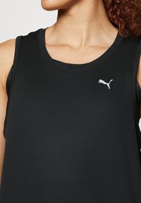 Débardeur athlétique noir à texture côtelée, coupe slim, avec un col rond, orné d'un petit logo Puma blanc sur la poitrine.