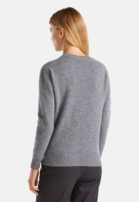 Szary sweter dzianinowy z okrągłym dekoltem, ściągaczami u dołu i przy mankietach, charakteryzujący się miękką teksturą i luźnym krojem. Widok z tyłu, pokazujący prostotę w designie.