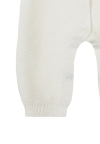 Weißer gestrickter Einteiler mit einem strukturierten Muster, der einen Knopfverschluss am Boden und gerippte Bündchen aufweist.