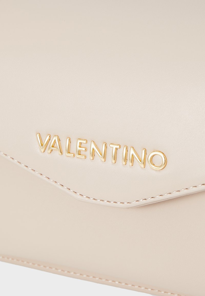 Clutch de cuero crema con solapa triangular, cuenta con el logo "VALENTINO" en relieve dorado y costura en contraste a lo largo de los bordes.