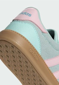 Světle modrá teniska z semišové a hladké kůže s růžovými detaily, texturovanou podrážkou a výrazným logem Adidas.