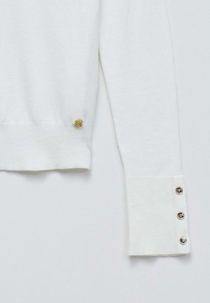Jersey blanco de punto con puños acanalados, acento del logo dorado y detalles de botones plateados en las aberturas de las mangas.