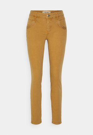 Jean slim fit jaune moutarde en denim, avec poches avant, couture décorative sur les poches, et une fermeture éclair avec bouton en métal.