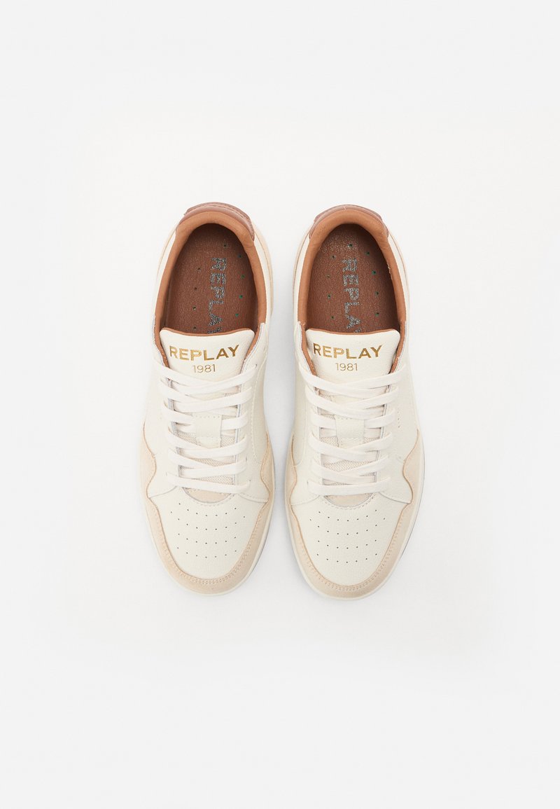 Weiß-beige Sneaker mit perforiertem Design, ausgestattet mit cremefarbenen Schnürsenkeln und goldener "REPLAY 1981"-Markierung auf der Zunge und den Innensohlen.