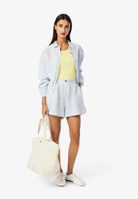 Modrá a bílá pruhovaná košile, žlutý top, související pruhované šortky, bílé tenisky a krémová taška. Neformální bavlněný outfit.
