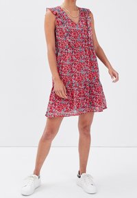 Red floral dress with ruffled sleeves, V-neck, and a flared hem. Lightweight fabric features blue and white accents, paired with white sneakers.