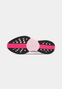 Des chaussures Nike avec une semelle extérieure en caoutchouc noir et rose, présentant un motif texturé et une semelle intermédiaire rose lisse. La tige affiche un design en mesh.