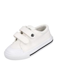 Zapatilla deportiva blanca de lona con correas de Velcro, puntera de goma y franja negra en la suela. Presenta un logo circular en el lateral.