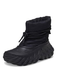 Svart vanntett boot med myk polstret overdel og teksturert gummisåle med bølgelignende design. Justerbar snøring for tilpasning.