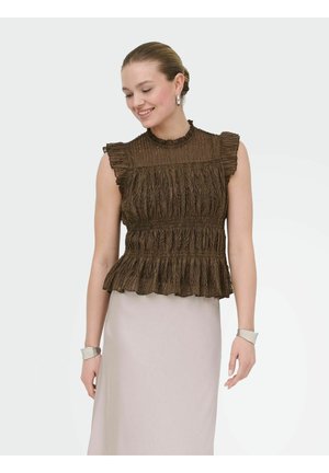 Femme souriante, portant un chemisier marron texturé sans manches avec des volants et une jupe beige clair, accessoirisée de boucles d'oreilles en argent et de bracelets blancs.