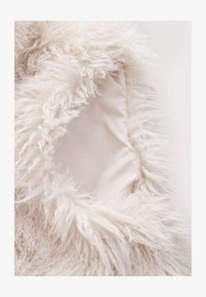 Pehme valge tekstiil pikkade, paksude kiududega ääres, mis paljastab siledat, helebeeži sisevoodrit. Pehme ja tekstuuriga välimus.