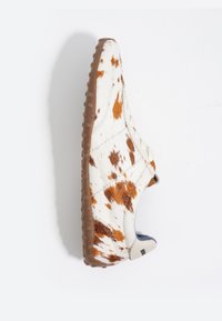 Zapato tipo slip-on hecho de material blanco con manchas marrones, con suela de goma texturizada y un interior azul a contraste. Diseño de punta redondeada.