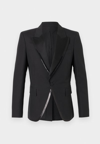 Veste de smoking noire à un bouton avec revers pointe en satin et poches à rabat, présentée sur un fond neutre.