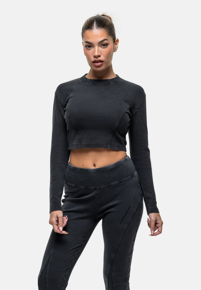 Top nero a maniche lunghe e taglio corto con texture a costine e collo rotondo, abbinato a pantaloni a vita alta coordinati con dettagli delle cuciture sottili.